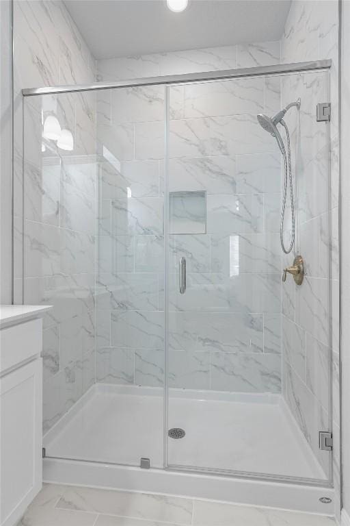 bathroom with marble finish floor, a shower stall, and vanity