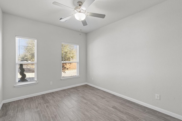 empty room featuring ceiling fan, baseboards, and wood finished floors