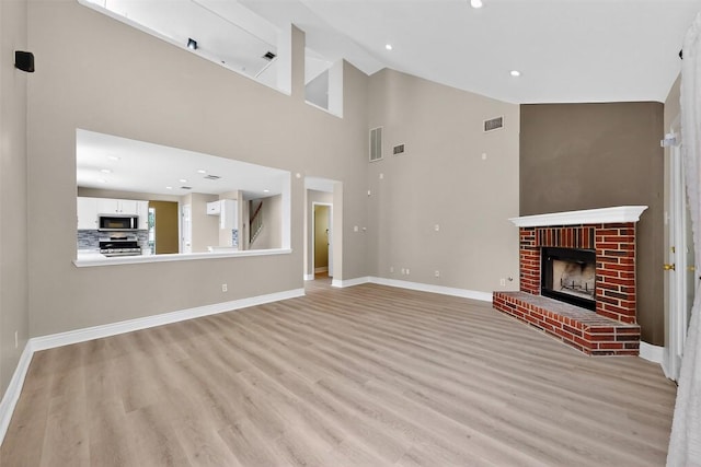 5008 Barlow Dr, Round Rock, TX 78681 - unfurnished living room featuring light wood-type flooring, high vaulted ceiling, a fireplace, and recessed lighting