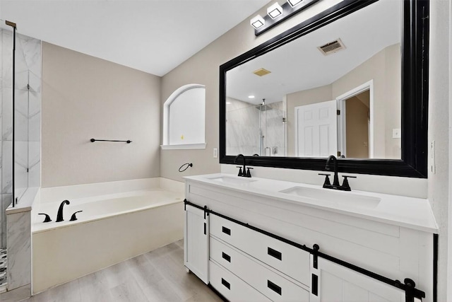 5008 Barlow Dr, Round Rock, TX 78681 - full bathroom featuring a garden tub, double vanity, a marble finish shower, and wood finished floors
