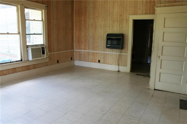 empty room with cooling unit, heating unit, wood walls, and light floors