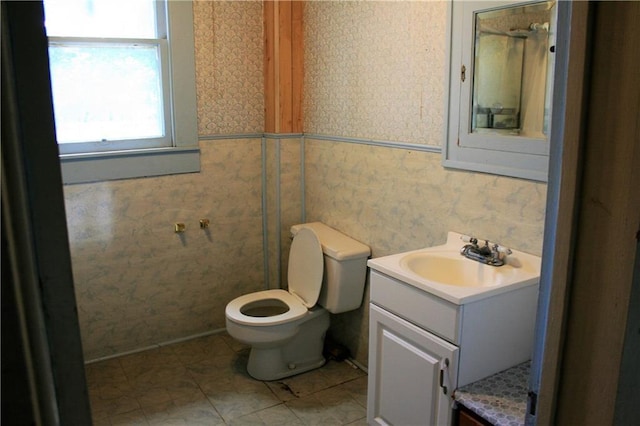 bathroom with vanity, toilet, and wallpapered walls