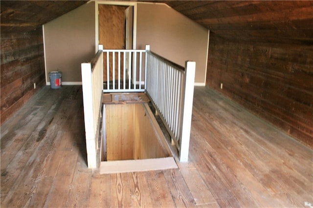 interior space featuring lofted ceiling, hardwood / wood-style flooring, and wood walls