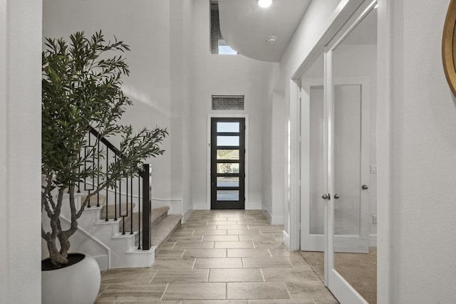 foyer with visible vents, a towering ceiling, stairway, wood tiled floor, and baseboards