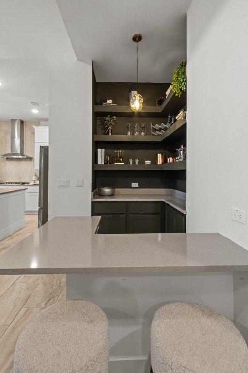 5824 Antelope Well Ln, Austin, TX 78738 - bar area featuring wall chimney exhaust hood, freestanding refrigerator, stovetop, and pendant lighting