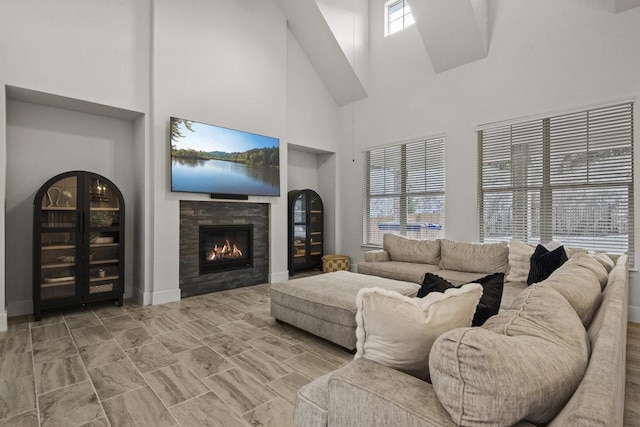 living room with a high ceiling, baseboards, and a tiled fireplace