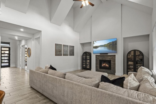 5824 Antelope Well Ln, Austin, TX 78738 - living area with high vaulted ceiling, a ceiling fan, a glass covered fireplace, light wood finished floors, and beam ceiling