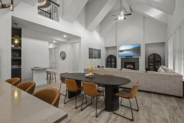 dining space with a lit fireplace, high vaulted ceiling, and beam ceiling