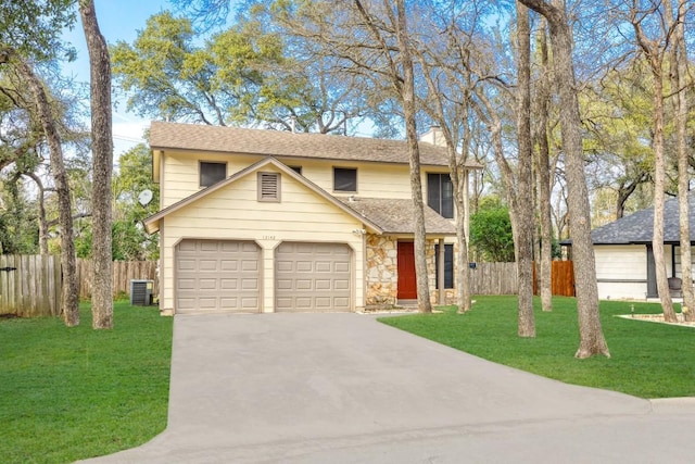 traditional-style home featuring driveway, a front lawn, an attached garage, and fence