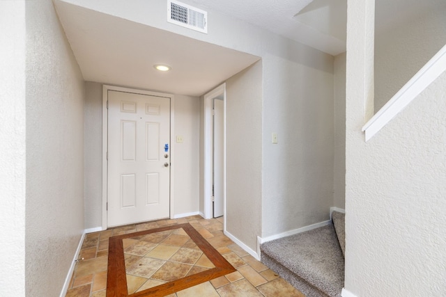 entrance foyer with visible vents, a textured wall, and baseboards