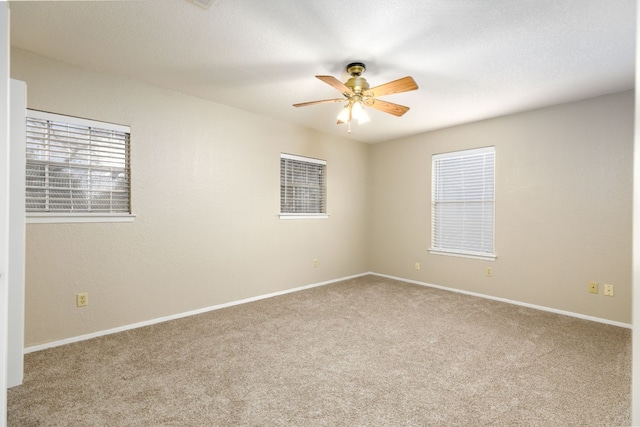 spare room featuring carpet floors, a wealth of natural light, and ceiling fan