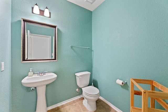 bathroom featuring toilet, a sink, visible vents, baseboards, and tile patterned floors