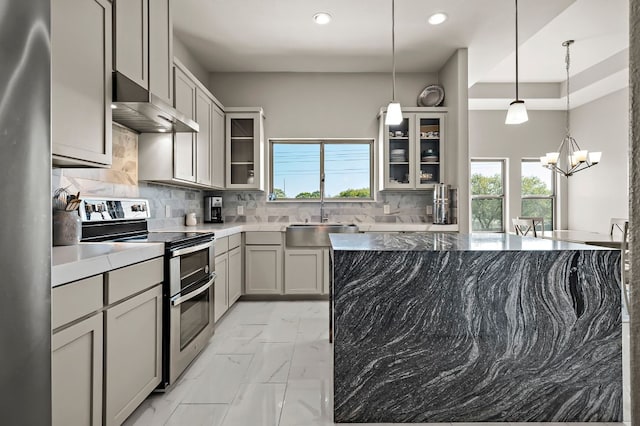 kitchen with decorative backsplash, appliances with stainless steel finishes, a healthy amount of sunlight, a sink, and wall chimney range hood