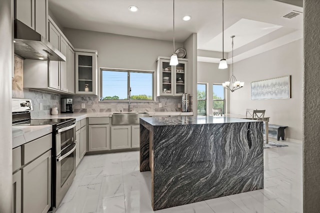 kitchen with visible vents, range with two ovens, wall chimney exhaust hood, gray cabinetry, and a sink