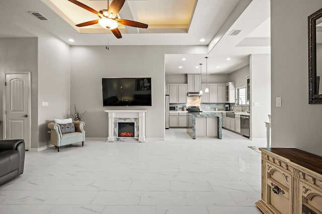 living area with marble finish floor, a premium fireplace, visible vents, and a raised ceiling