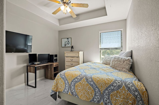 bedroom featuring a raised ceiling, ceiling fan, marble finish floor, and baseboards