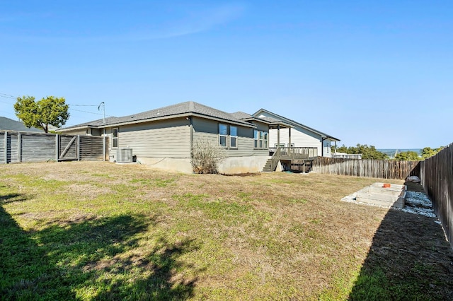 back of property featuring cooling unit, a gate, a fenced backyard, and a lawn