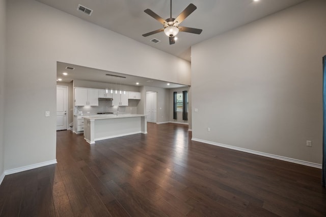 unfurnished living room with a ceiling fan, baseboards, visible vents, and dark wood-type flooring