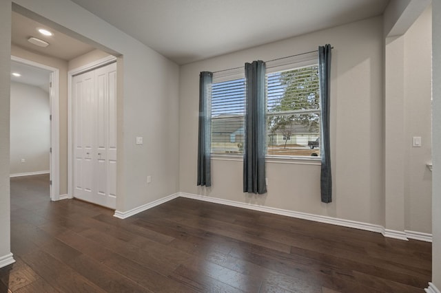 spare room with dark wood-style flooring and baseboards