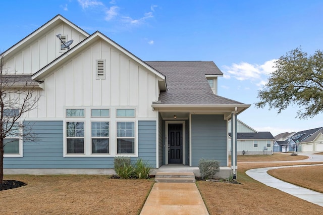 view of front of home with a shingled roof, a front lawn, and board and batten siding