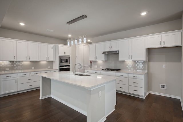 kitchen featuring dark wood-style flooring, stainless steel appliances, white cabinets, a sink, and under cabinet range hood