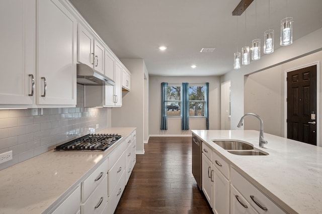 kitchen with backsplash, appliances with stainless steel finishes, white cabinetry, a sink, and under cabinet range hood