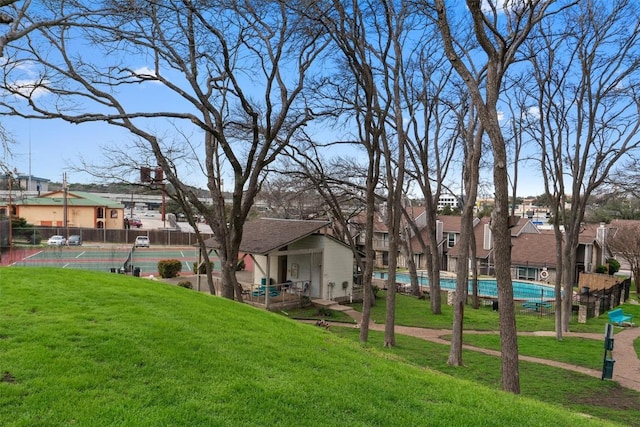 view of yard with a tennis court, fence, and a residential view