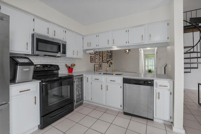 kitchen featuring appliances with stainless steel finishes, beverage cooler, light countertops, and a sink