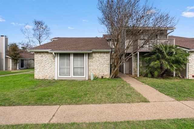 view of front of property featuring a shingled roof, stone siding, and a front lawn