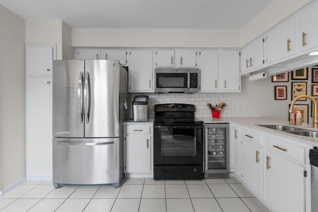 kitchen featuring light tile patterned floors, wine cooler, appliances with stainless steel finishes, a sink, and backsplash