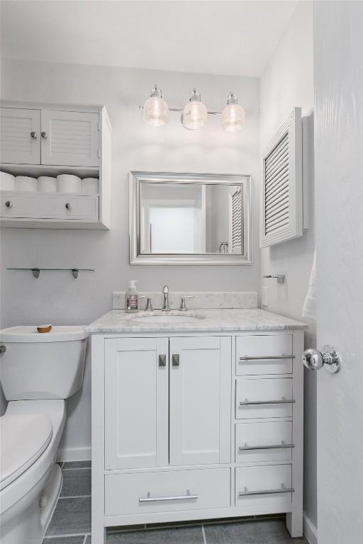 bathroom featuring baseboards, vanity, and toilet