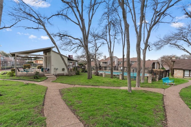 surrounding community featuring a residential view, a lawn, a swimming pool, and fence