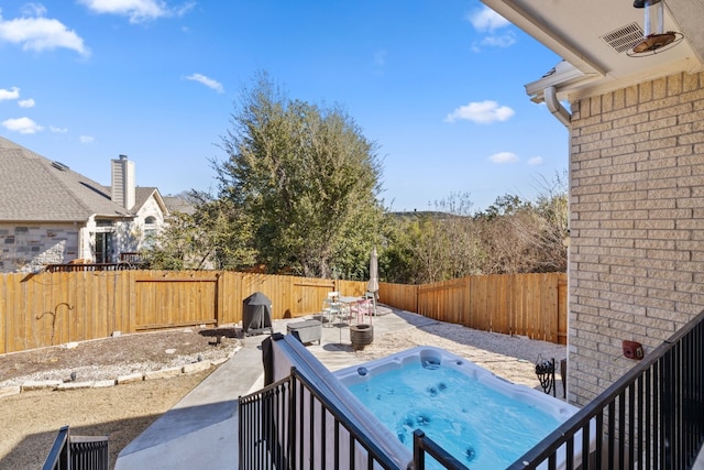 exterior space featuring a hot tub, a fenced backyard, and a patio