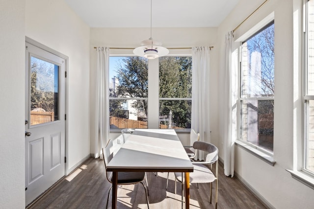 dining room with dark wood-type flooring, plenty of natural light, and baseboards