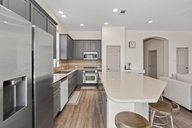 kitchen featuring stainless steel appliances, a sink, a kitchen island, visible vents, and gray cabinets