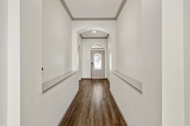 doorway to outside featuring baseboards, arched walkways, crown molding, and wood finished floors