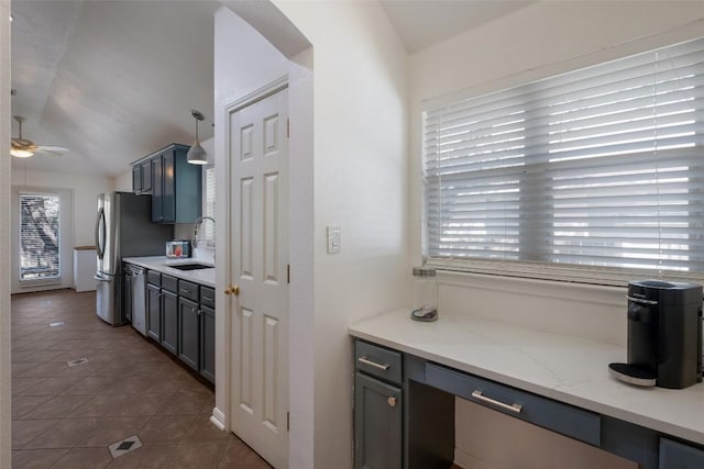 kitchen featuring lofted ceiling, stainless steel dishwasher, dark tile patterned floors, and a sink