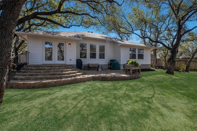 ranch-style house with a patio, french doors, a front yard, and fence