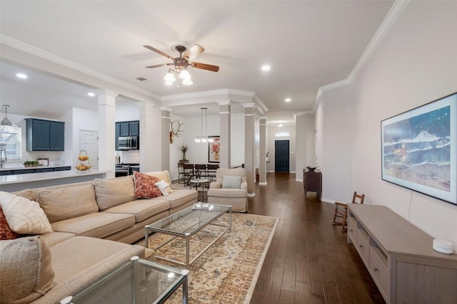 living room with crown molding, decorative columns, recessed lighting, dark wood-type flooring, and ceiling fan