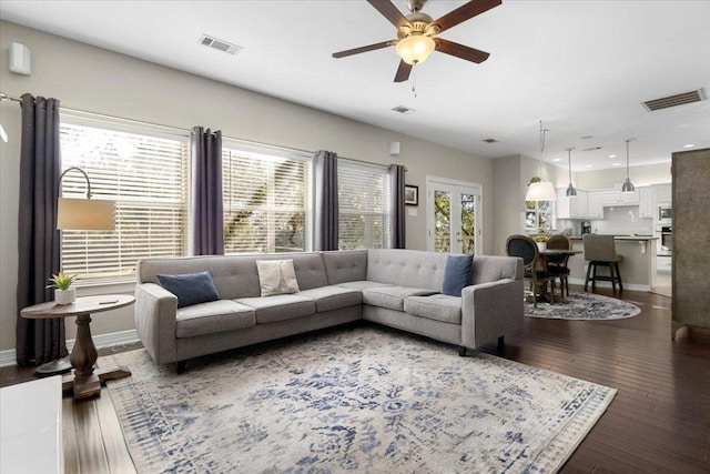 living area with hardwood / wood-style flooring, baseboards, visible vents, and a wealth of natural light