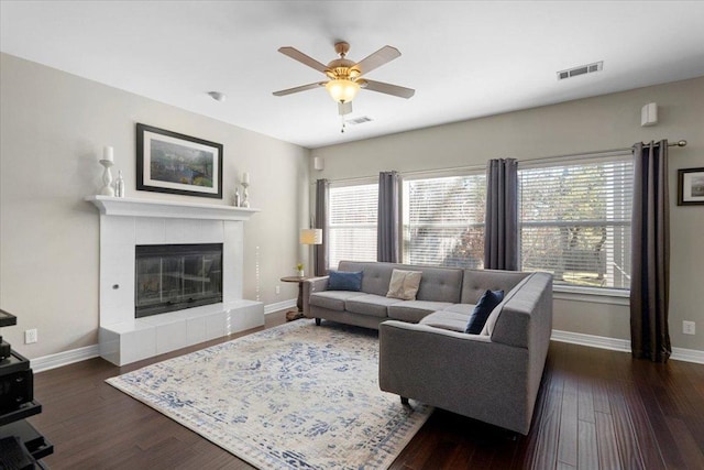 living room with baseboards, a fireplace, visible vents, and dark wood-style flooring