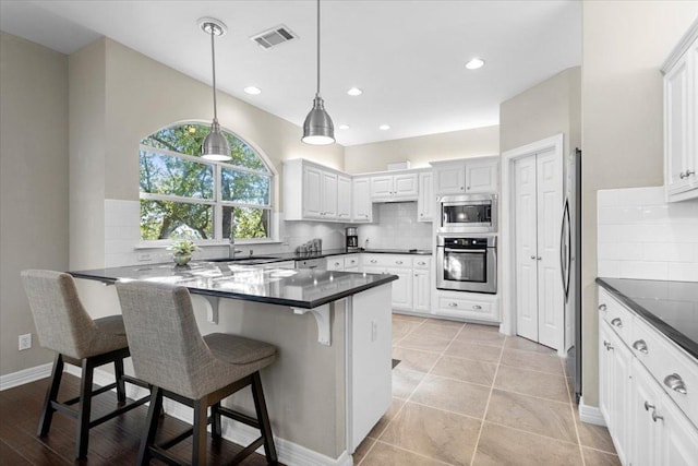 kitchen featuring a peninsula, dark countertops, appliances with stainless steel finishes, and backsplash