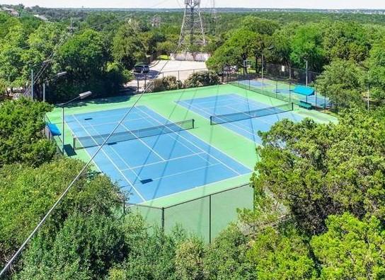 view of sport court featuring a forest view and fence