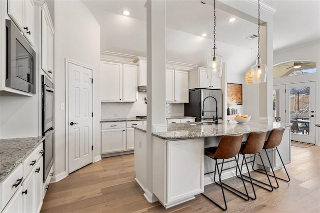 kitchen with light wood-type flooring, appliances with stainless steel finishes, white cabinets, and crown molding