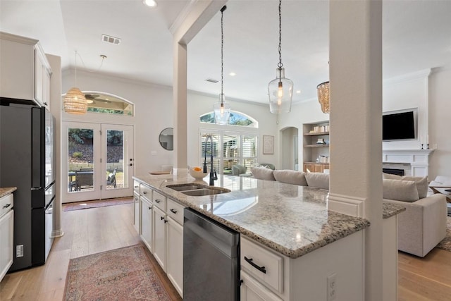 kitchen featuring freestanding refrigerator, open floor plan, a sink, and stainless steel dishwasher