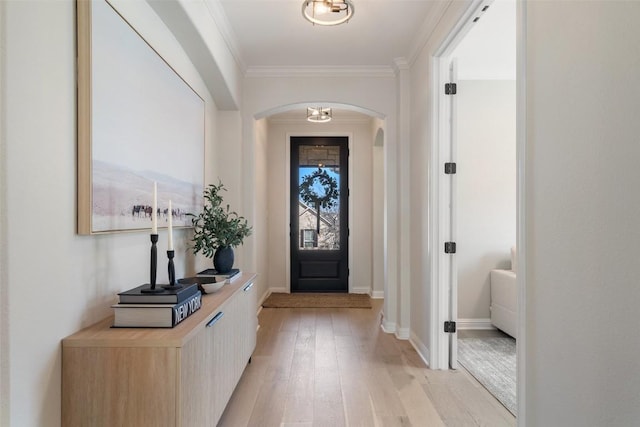 entryway featuring light wood-style floors, arched walkways, ornamental molding, and baseboards