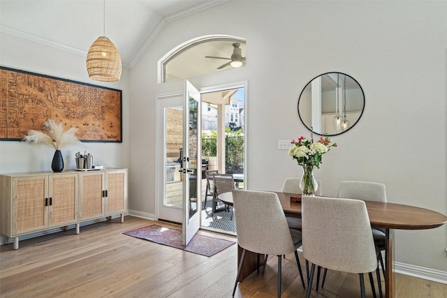 dining room featuring light wood-type flooring, lofted ceiling, ornamental molding, and baseboards