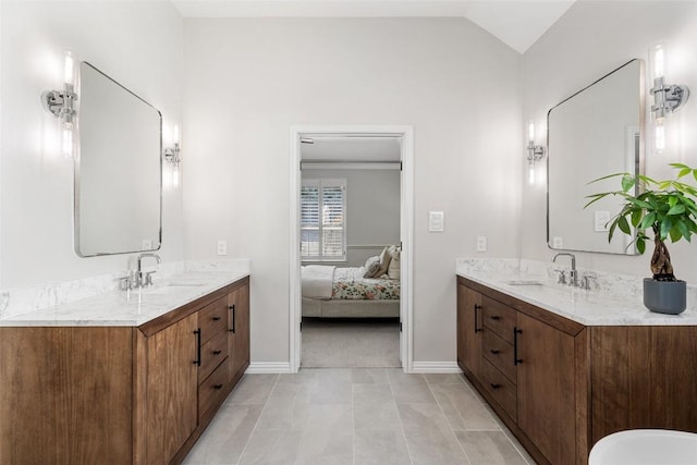 bathroom featuring lofted ceiling, two vanities, and a sink