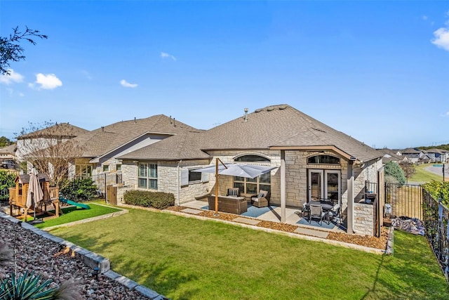 back of house with stone siding, a patio area, a lawn, and an outdoor living space