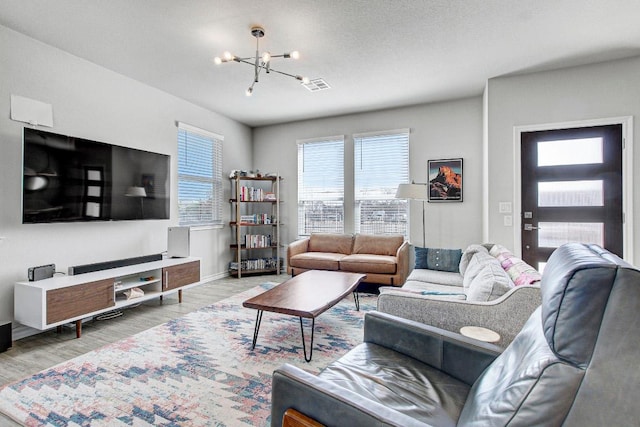 living area with baseboards, visible vents, a notable chandelier, and wood finished floors